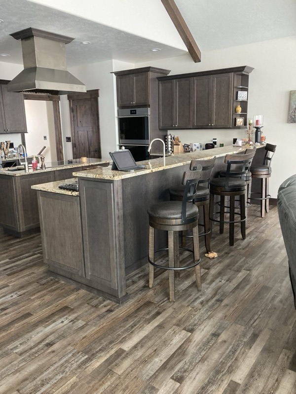 Kitchen with dark cabinetry, stone countertop island, and bar seating