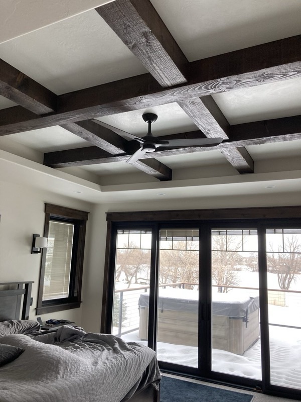 Bedroom with vaulted ceiling, reclaimed wood accent wall, and large windows