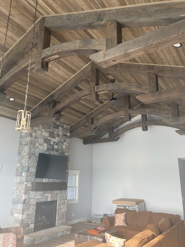 Great room with vaulted ceiling, exposed timber trusses, and stone fireplace