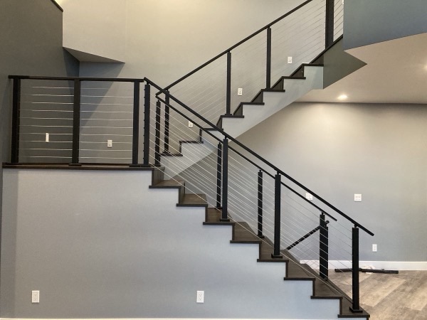 Modern staircase with black cable railing and hardwood treads